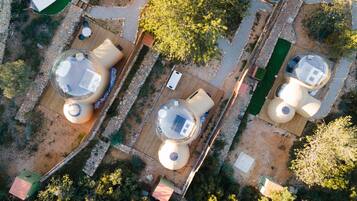Vista aérea de un complejo turístico con varias habitaciones esféricas, un sendero central y abundante vegetación.