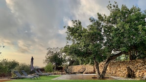 A swimming pool with lounge chairs and a stone wall.