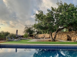 Piscina com espreguiçadeiras e uma parede de pedra.