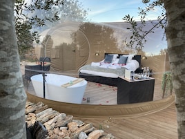 Quarto com uma cama grande, banheira e um deck de madeira.
