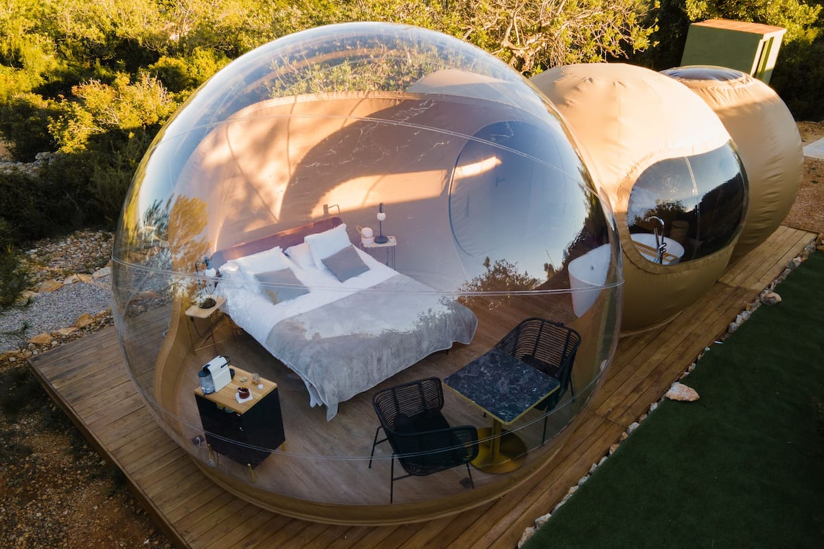 Une structure en forme de dôme transparent, à l’intérieur de laquelle se trouvent un lit, une table et deux chaises.