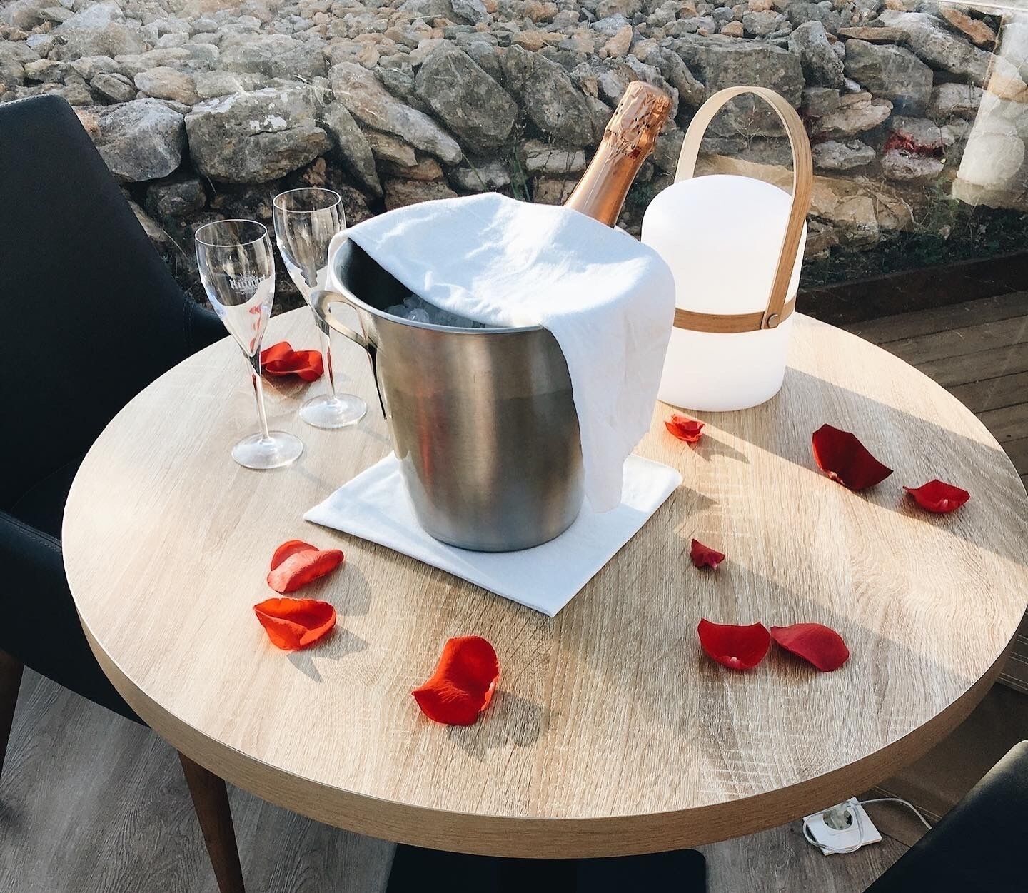 A round wooden table with a metal bucket, a white bucket, and a glass of water.