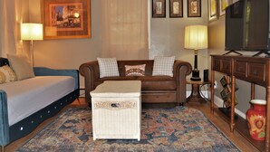 A room with a sofa, a small table, a television, and a decorative lamp. - The Red 6 at Grand Forks (Grand Forks)
