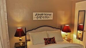 A neatly made bed with two lamps on either side, a decorative pillow, and a wall sign. - The Red 6 at Grand Forks (Grand Forks)