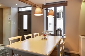 Un comedor con una mesa de madera, sillas blancas e iluminación colgante.