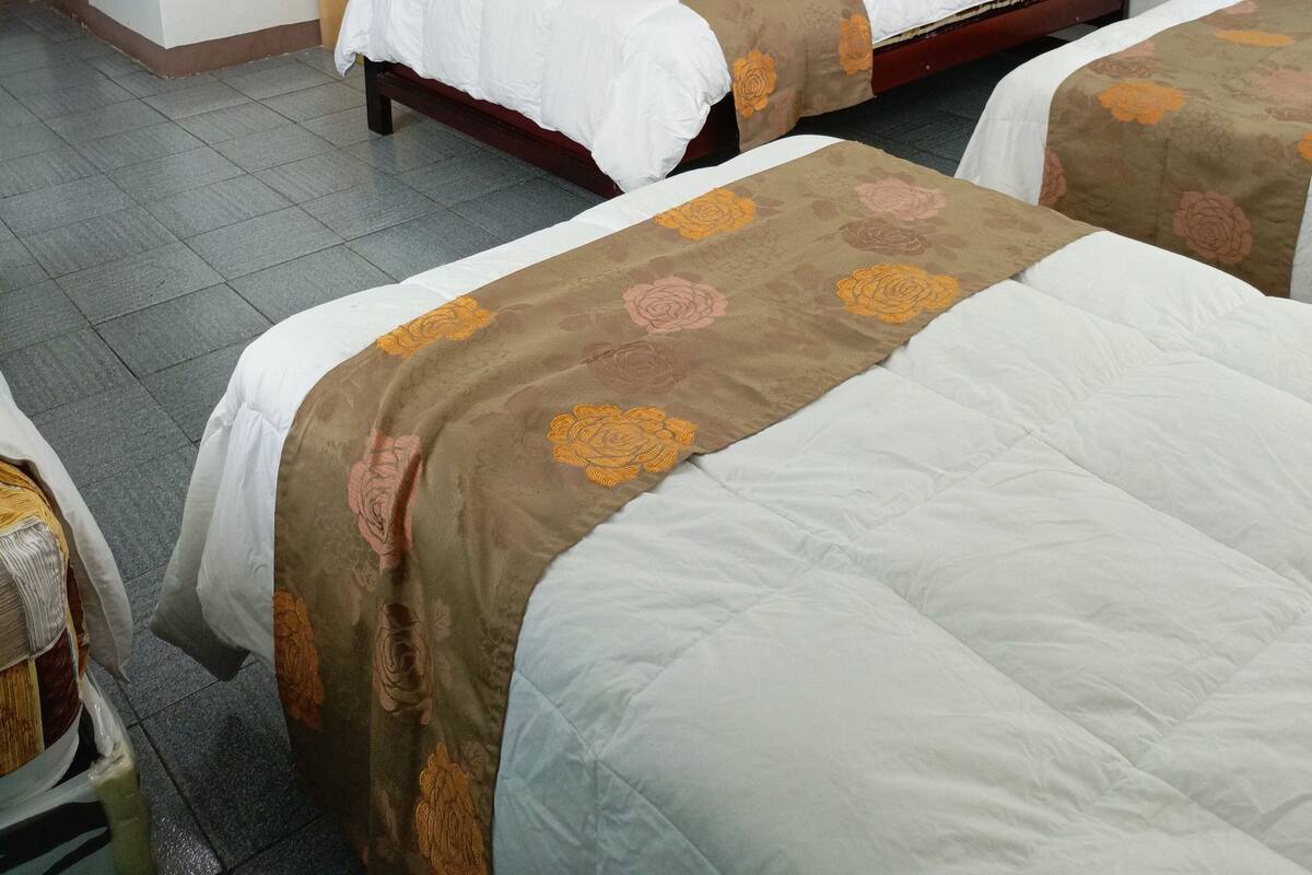 A hotel room with two beds, a desk, and a painting on the wall.