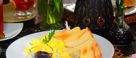 Un desayuno con tostadas, huevos revueltos y fruta.