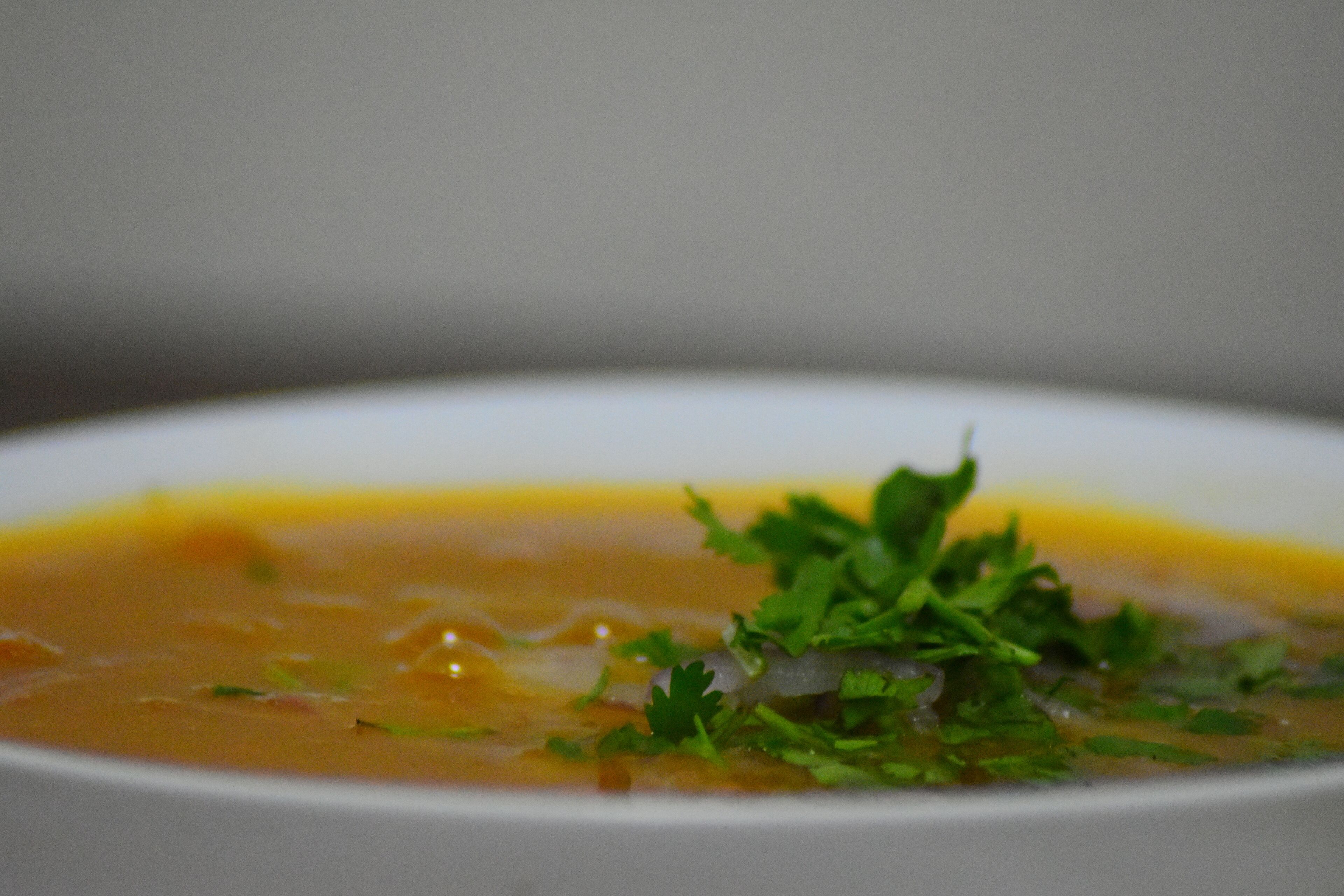 A bowl of soup with a garnish of green herbs.
