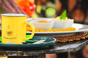 A yellow mug with a café logo on a green saucer.
