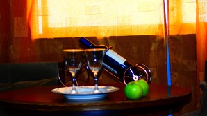 Una mesa con un plato, dos vasos, una botella y una manzana verde.