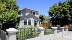 A two-story house with a front yard and a white fence.