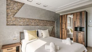 A modern bedroom with a large bed, wooden wardrobe, and a unique wall art piece. - Appartement Haut Standing Tanger (Tangier)