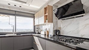A modern kitchen with a gas stove, marble countertops, and a view of the city through large windows. - Appartement Haut Standing Tanger (Tangier)