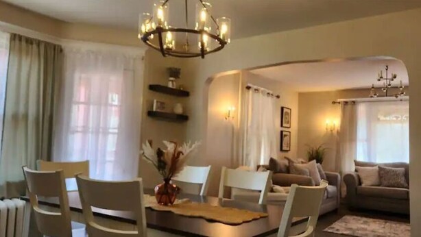 Una sala de estar acogedora con comedor, que incluye una araña, sofás y una chimenea.