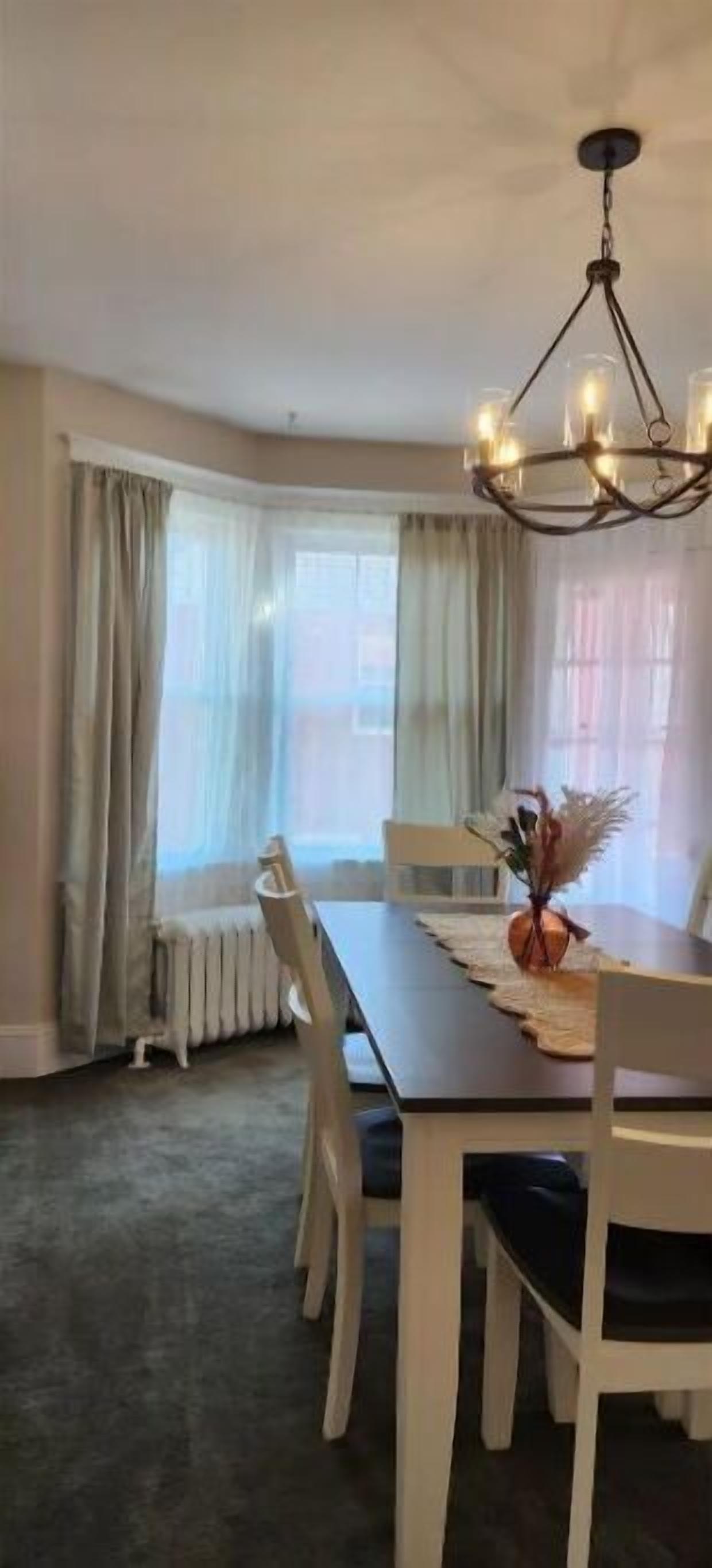 A dining area with a dark wooden table, white chairs, and a chandelier.