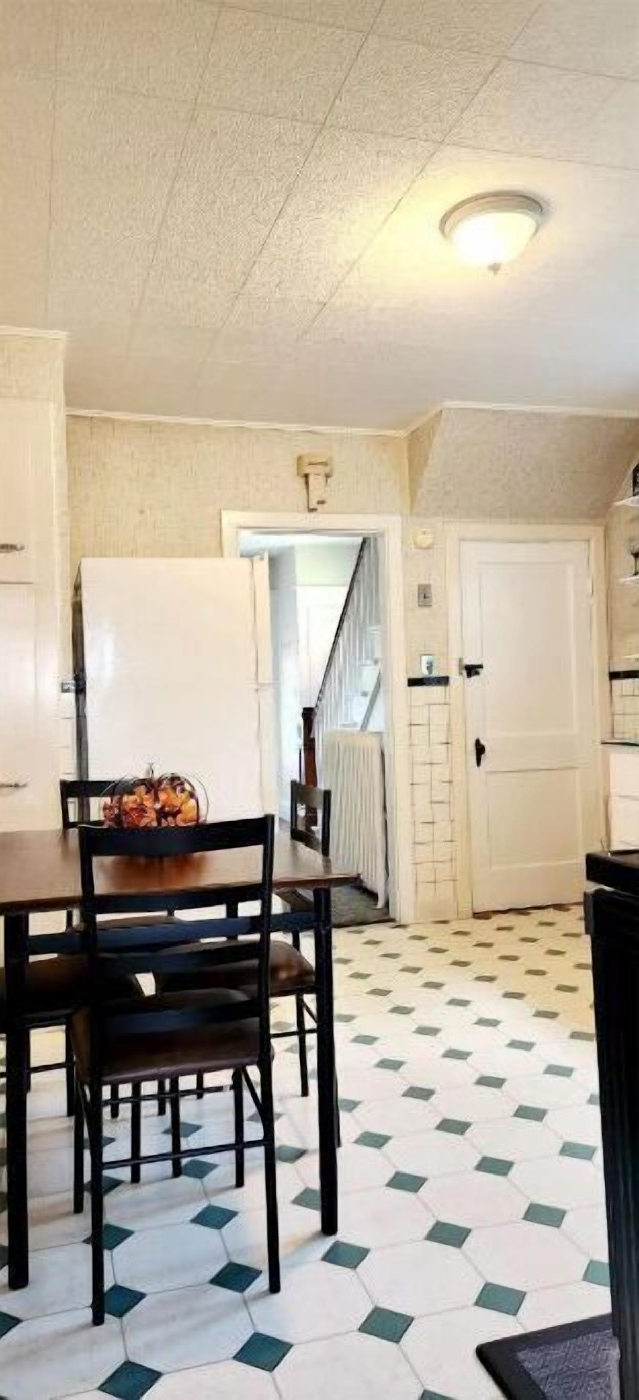 Un comedor con una mesa y sillas, un refrigerador y un suelo estampado.