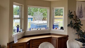 Une pièce d’angle avec un bureau, trois fenêtres et un ventilateur de plafond.