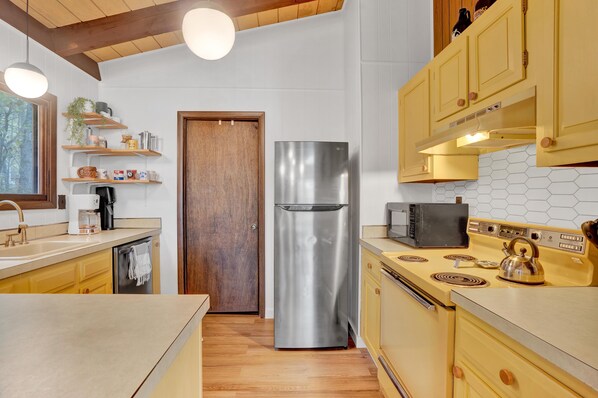 Une cuisine moderne dotée de meubles en bois, d’un réfrigérateur en acier inoxydable, d’un four à micro-ondes et d’une bouilloire.