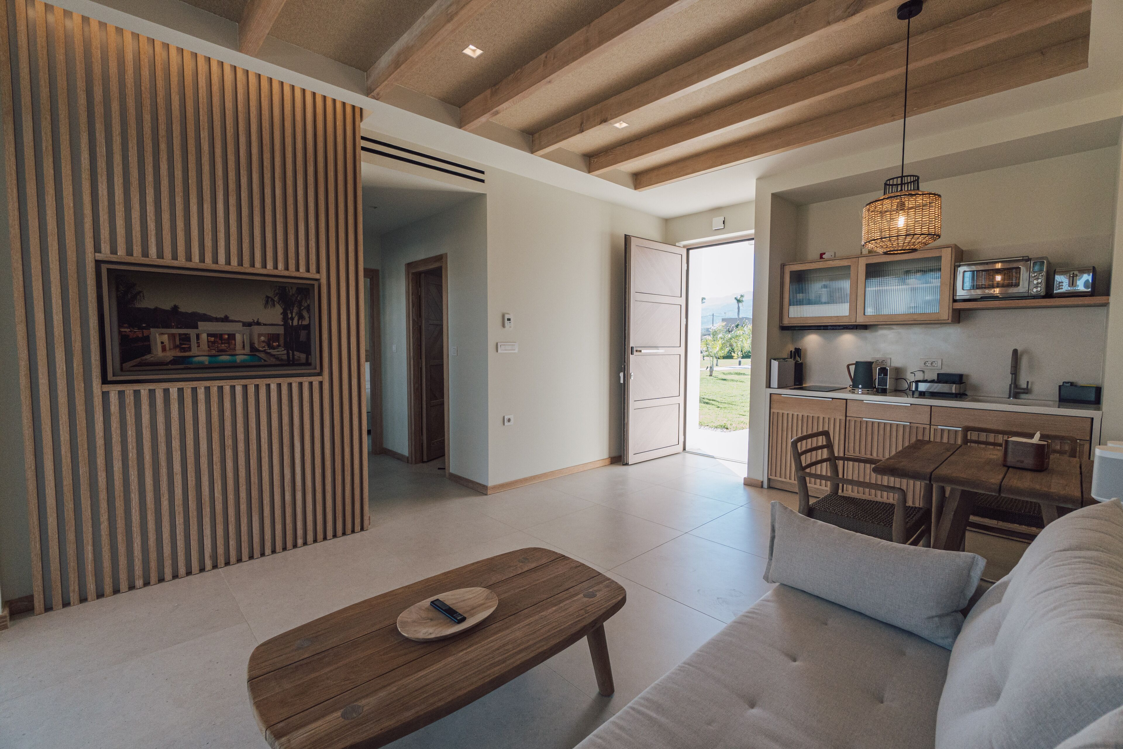 A modern living room with a wooden bench, a sofa, and a dining area with a table and chairs.