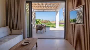 A modern room with a sofa, a wooden table, and a view of an outdoor patio with a table and chairs.