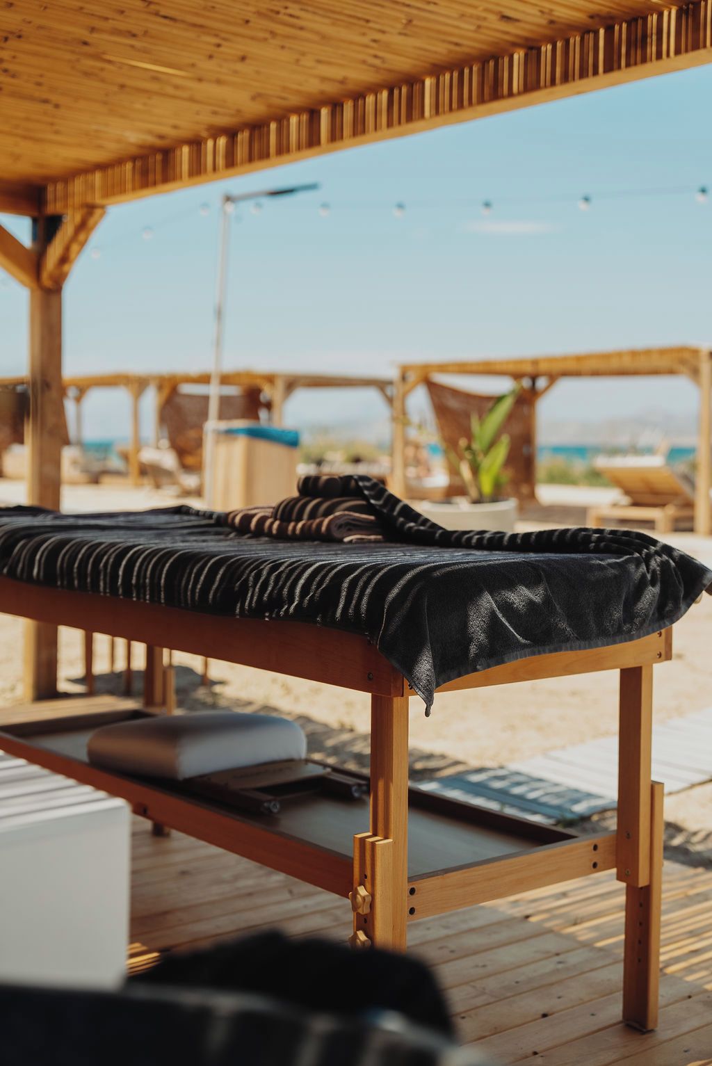 Una terraza de madera con una cama individual, una mesita y un banco.
