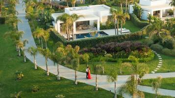 A modern resort with a pool, palm trees, and a well-maintained lawn.