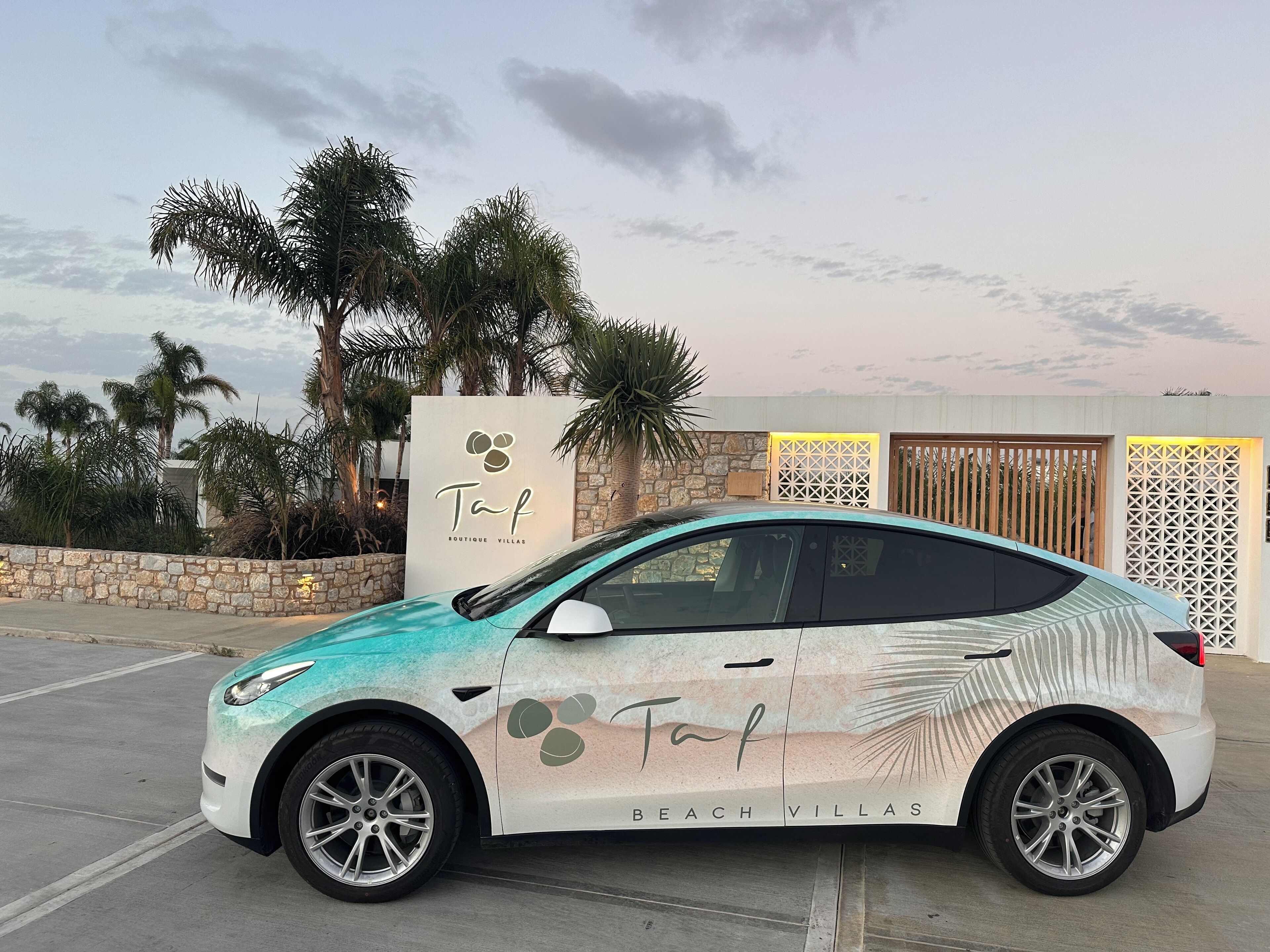 Une voiture est garée devant un immeuble sur lequel on peut lire l’inscription « Taf Boutique Villas ».