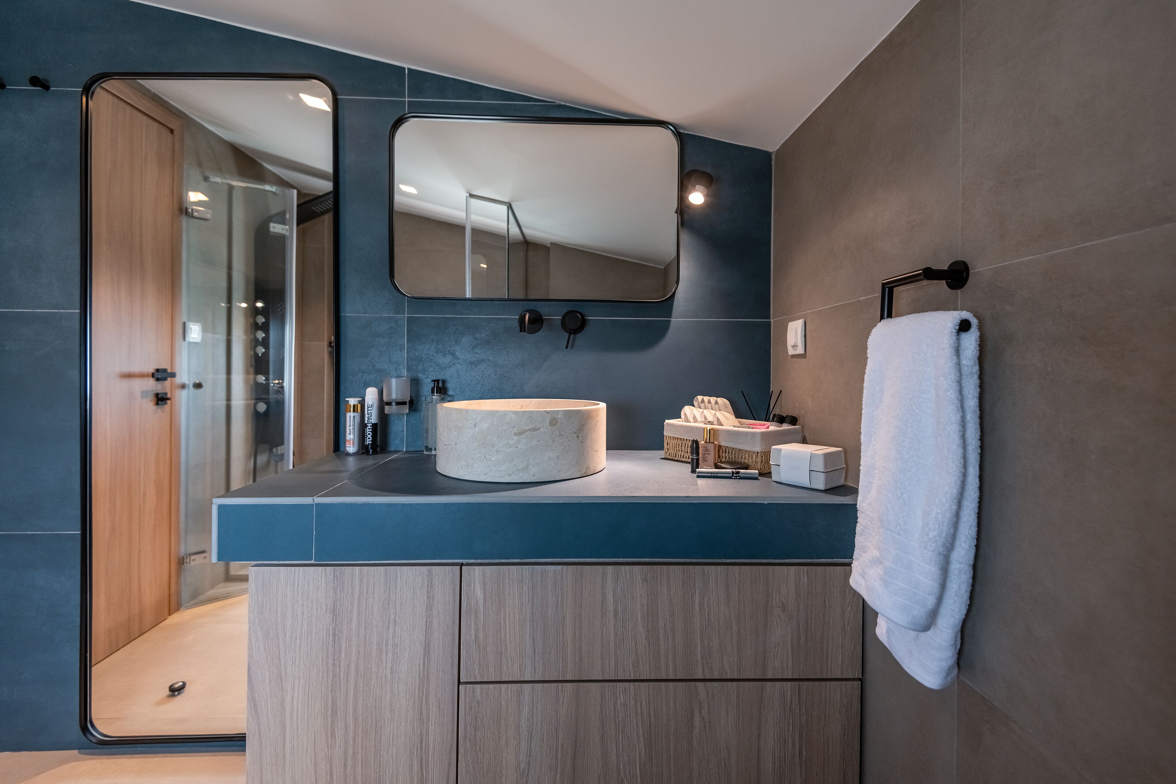 Une salle de bain moderne avec un grand miroir, un lavabo rond et un porte-serviettes.