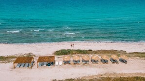 Una spiaggia con una fila di lettini e una piccola capanna.