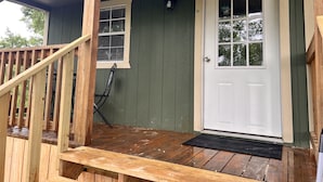 Una terraza de madera con una puerta y una ventana blancos.