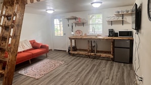 Una cocina compacta con una mesa de madera, un sofá rojo y un refrigerador pequeño.