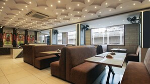 A restaurant with booth seating, a reception area, and large windows. - Itsy Hotels Yogeshwara Grand (Hyderabad)