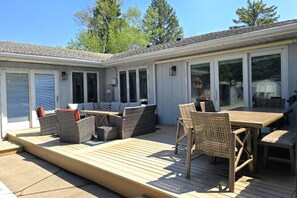 A covered patio with outdoor furniture, a deck, and a building with large windows and doors. - 🔥 Pool + Hot Tub + Sauna | Fargo’s Ultimate Stay (Fargo)