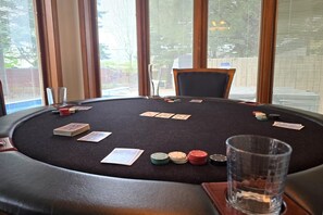 Pokeriin tarkoitettu pöytä, jossa on kortteja ja pelimerkkejä, tuoli ja lasi vettä.