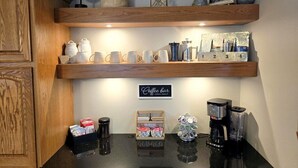 Een keuken met houten planken, een bord met daarop 'Coffee Bar' en diverse koffiezetapparaten.