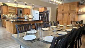 Een moderne keuken met houten kastjes, een centraal eiland en een eettafel gedekt voor zes personen.
