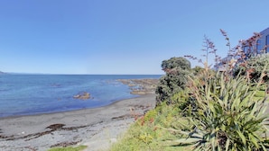 Une vue sur la côte, avec une plage de sable, une côte rocheuse et une eau d’un bleu limpide.