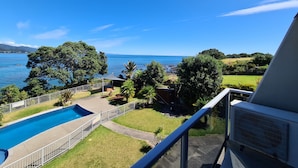 Une piscine avec vue sur la mer, entourée de verdure et délimitée par une clôture.