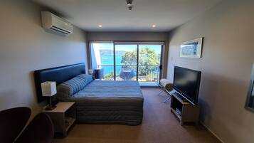 A modern hotel room with a large bed, a flat-screen TV, a desk, and a chair.