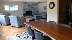 A modern kitchen with a stone backsplash, a dining area with a wooden table, and a living room with a gray sofa and a fireplace. - Gorgeous home w/Sauna downtown Anchorage. Walk to dine, coffee & attractions (Anchorage)