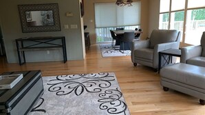 A spacious living room with a large sofa, a dining area with a table and chairs, and a kitchen area with a countertop and cabinets. - Gorgeous home w/Sauna downtown Anchorage. Walk to dine, coffee & attractions (Anchorage)