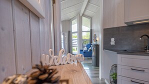 A modern kitchen with a wooden countertop, a welcome sign, and a view into the living area. - Baltic View - Komfortables, Sehr Strandnahes Ferienhaus mit Whirlpool und Sauna (Brodersby)