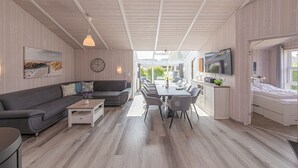 A modern interior with a sofa, dining table, TV, and wooden flooring. - Baltic View - Komfortables, Sehr Strandnahes Ferienhaus mit Whirlpool und Sauna (Brodersby)