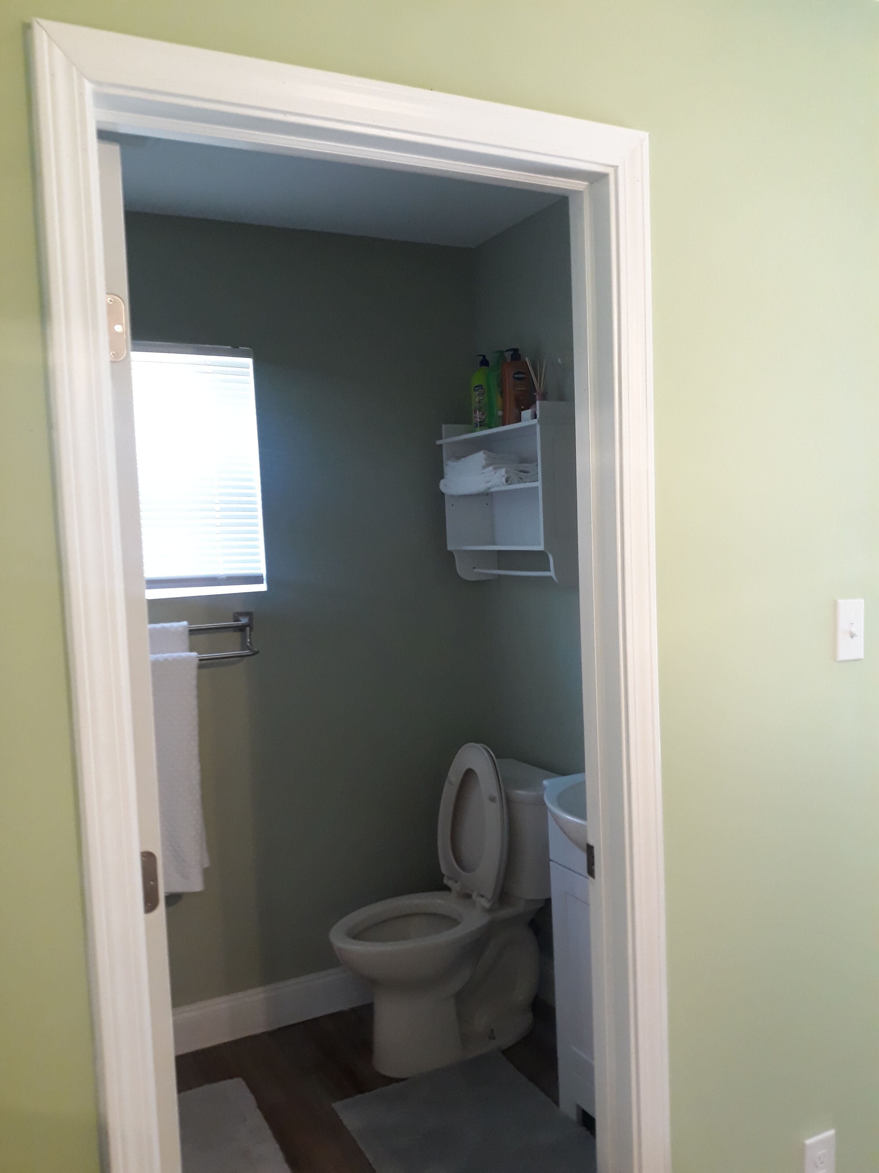 Une petite salle de bain comprenant des toilettes, un lavabo et une étagère avec des articles de toilette.