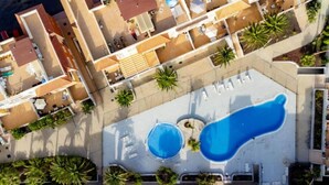 An aerial view of a hotel with multiple buildings, a central pool area, and surrounding palm trees. - Ground-Floor 1 bedroom condoPool &Wifi Costa Adeje (Callao Salvaje)