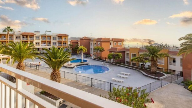 A hotel courtyard with a swimming pool, palm trees, and a view of the surrounding buildings. - Ground-Floor 1 bedroom condoPool &Wifi Costa Adeje (Callao Salvaje)