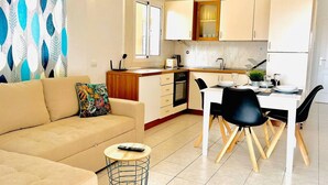 A modern kitchen with white cabinets, a dining area with black chairs, and a beige sofa with a colorful pillow. - Ground-Floor 1 bedroom condoPool &Wifi Costa Adeje (Callao Salvaje)