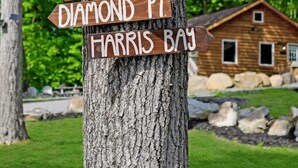 A wooden signpost with multiple directional arrows pointing to various locations such as Bolton Landing, Kattskill Bay, and Harris Bay. - Walk to Beach - Close to Town - Pet Friendly Cabin (Lake George)