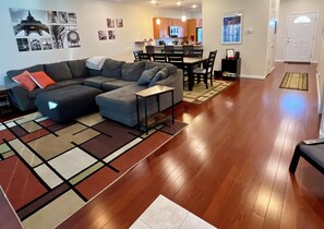 Uma sala de estar moderna com um sofá seccional, uma mesinha e um espaço de jantar com cadeiras.