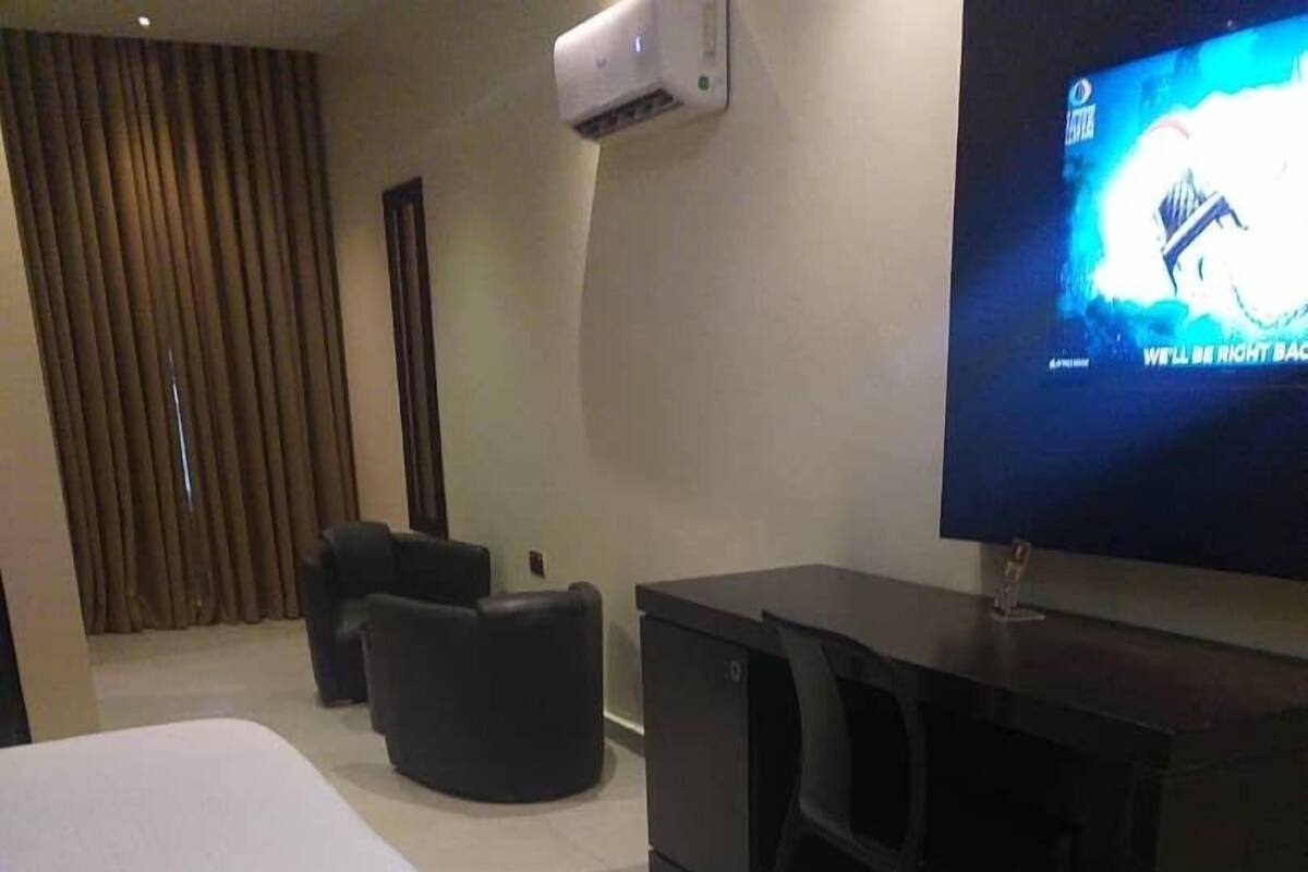 A hotel room with a large bed, a desk, a chair, and a television on the wall.